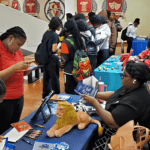Students at a college fair with tables.