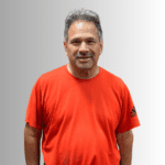 Smiling man in red shirt against gradient background.