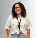 Smiling woman with curly hair in white shirt.