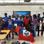 Group celebrating with Haitian flags in classroom.
