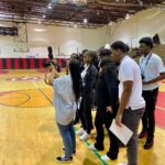 Students filming in a gymnasium setting.